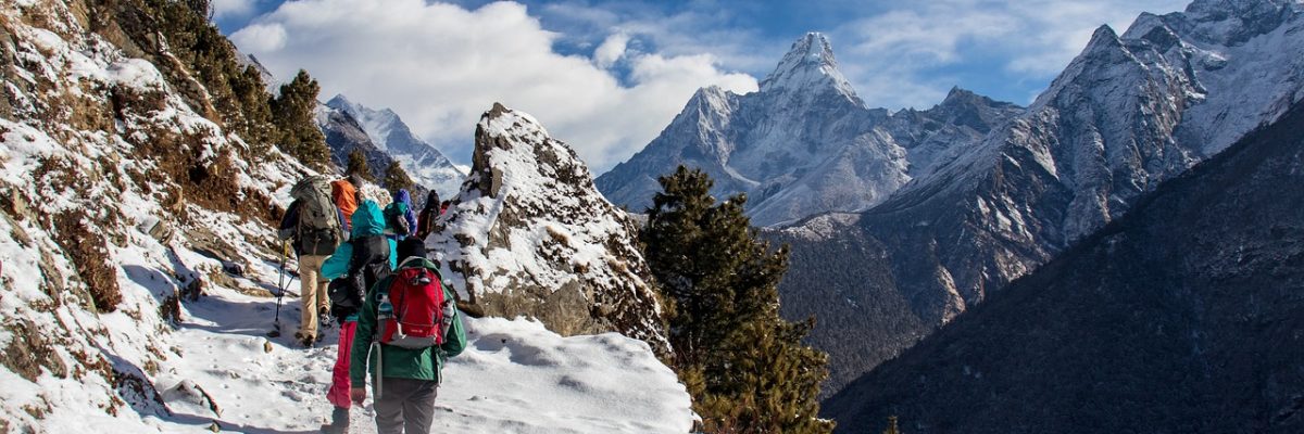 People hiking in snow in the Himalayas with Everest in the background, travel destinations hub